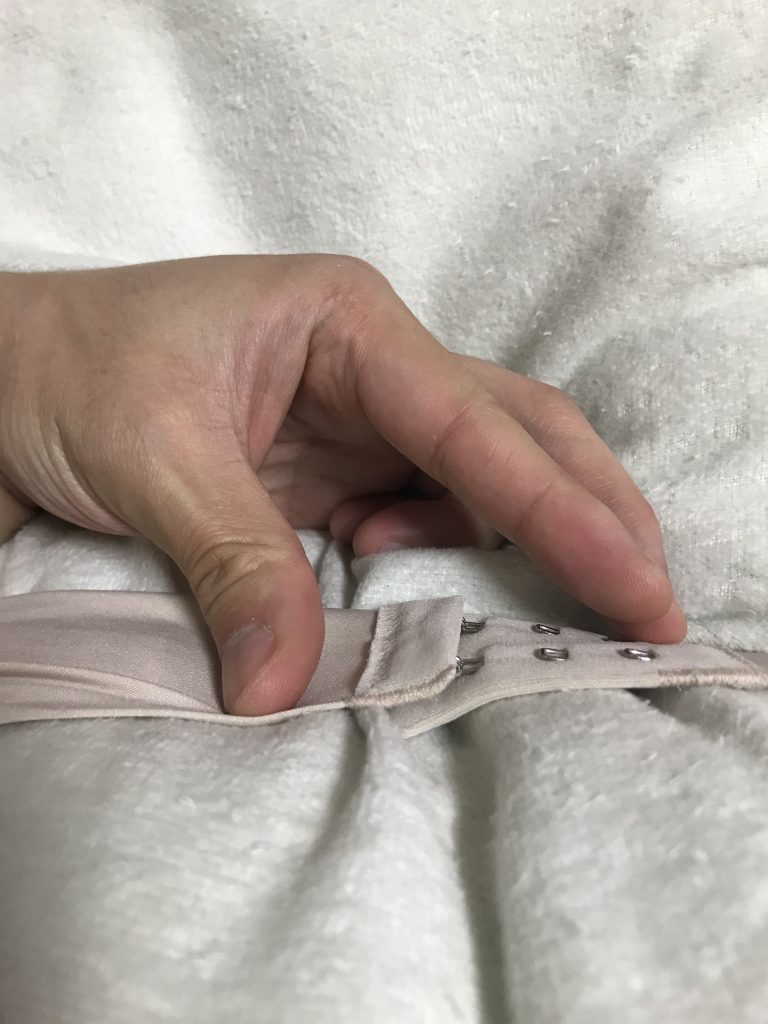 ブラジャーのはずし方の手順画像：①右手で女の子の背中に左から手を回してホックを確認